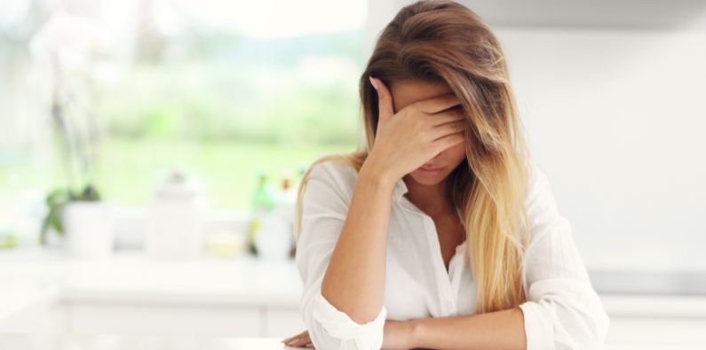 frau mit kopfschmerzen legt den Kopf in die hand